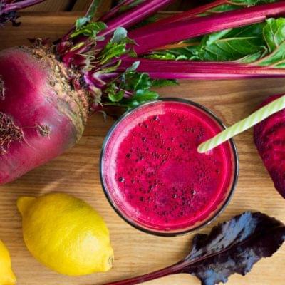 beetroot juice in glass top down view with lemon and lettuce